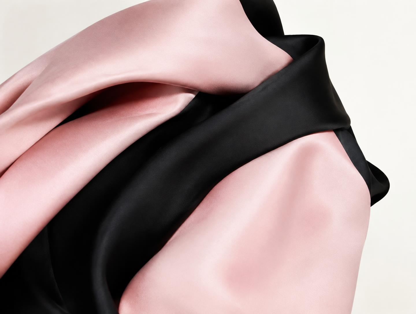 Close-up of pink and black satin folds shot as a fashion editorial texture